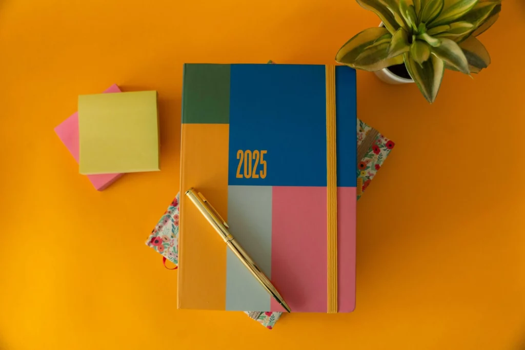 2025 planner notebook with pen and succulent on orange desk