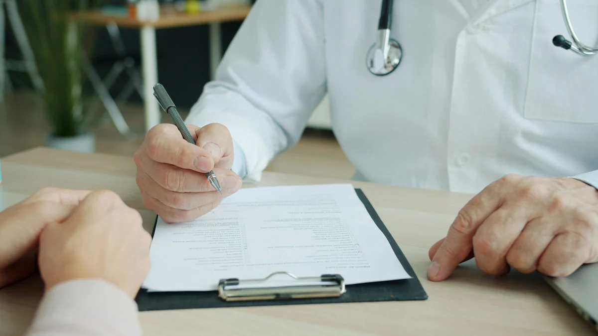 Clinician writing notes on a clipboard during a patient visit