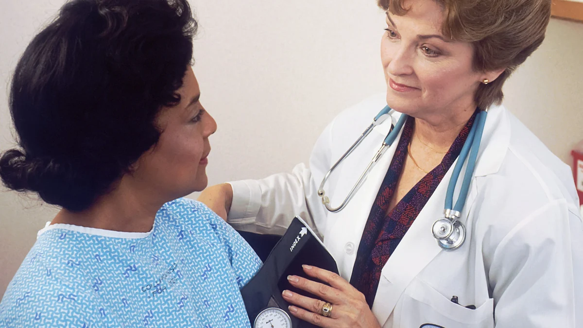 Doctor checking a patient's blood pressure in an exam room