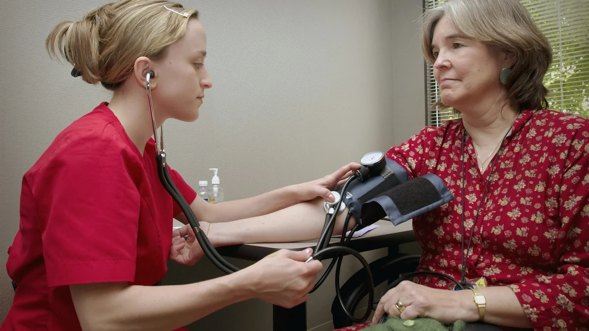 Nurse measuring a woman's blood pressure in a clinic