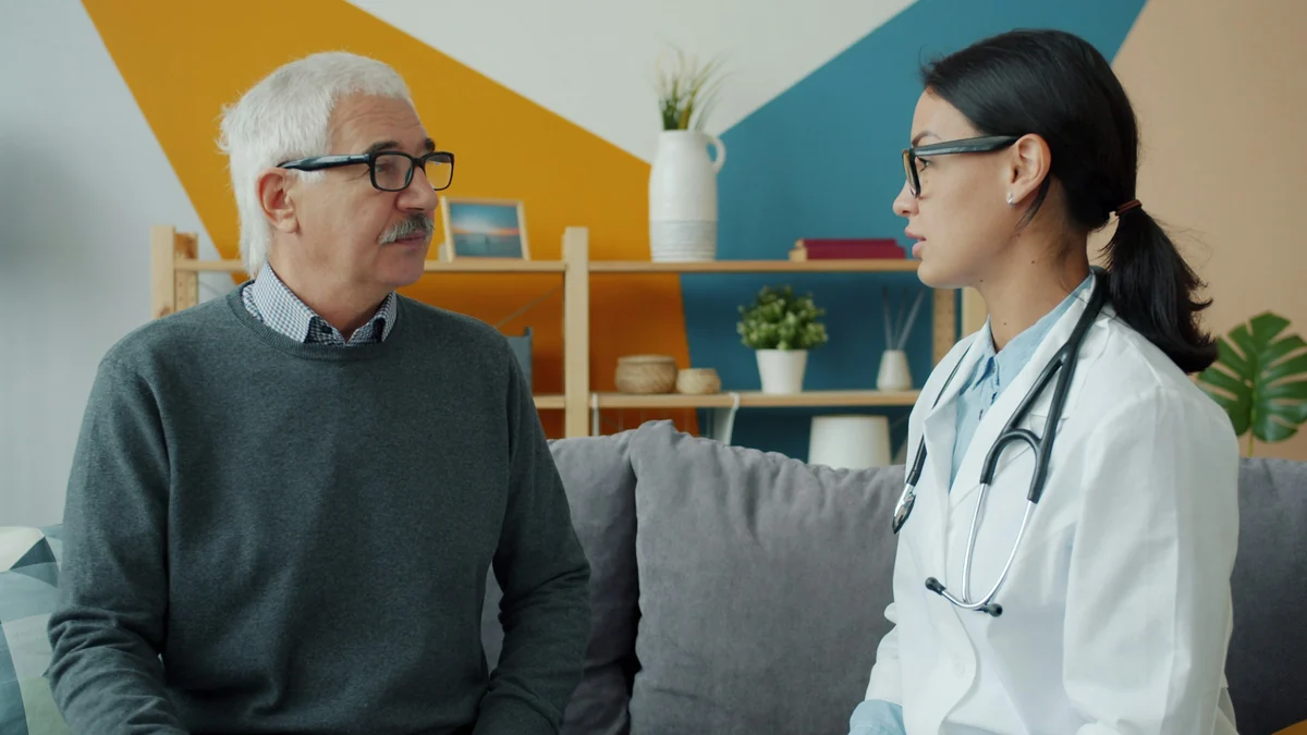 Older man talking with a doctor in a bright room