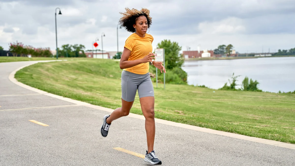 Woman jogging on a park path beside a river